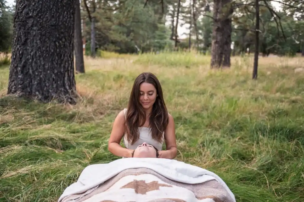 Katrinna Jasso performing cranial massage outdoors in a forest meadow
